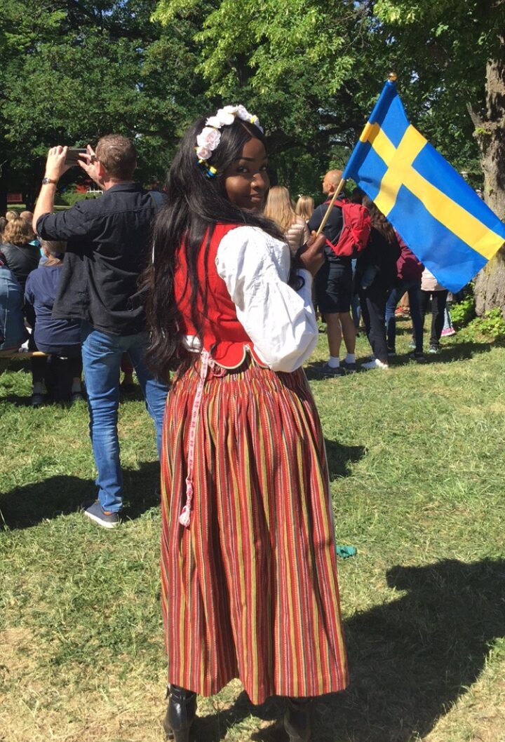 Lovette Jallow wearing traditional swedish clothing wavibg swedish flag