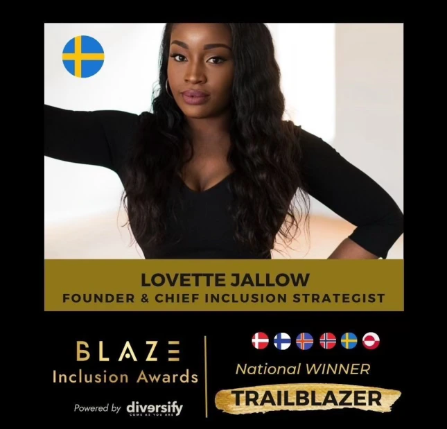 Lovette Jallow, the Blaze Inclusion Awards National Winner for Sweden in the Trailblazer category, standing with one arm raised against a pillar, dressed in black.