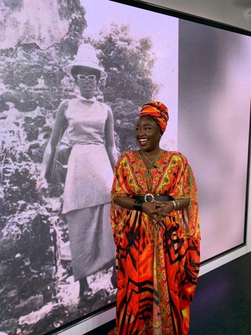 Lovette Jallow standing in front of an image of her grandmother at Swedish Tv SVT1